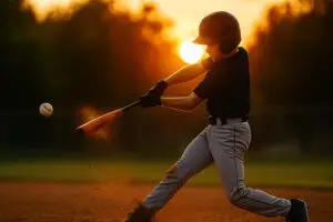 player development young player hits baseball at sunset at practice focusing on development over games